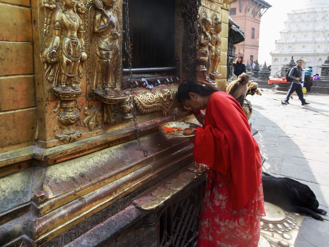 A woman in red praying at a shrine