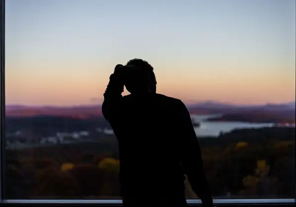 A man at a window looking out over the valley at dusk
