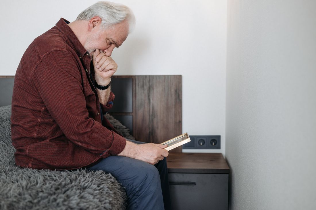 An older man holding a framed photograph, remembering
