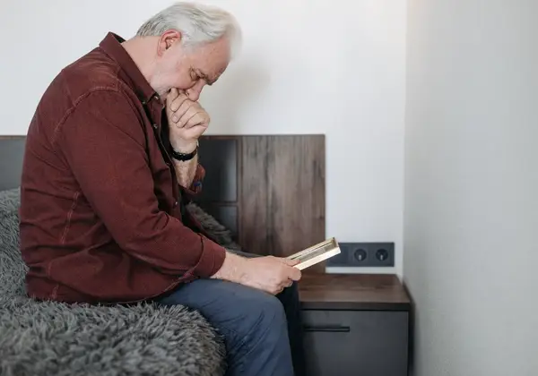 An older man holding a framed photograph, remembering
