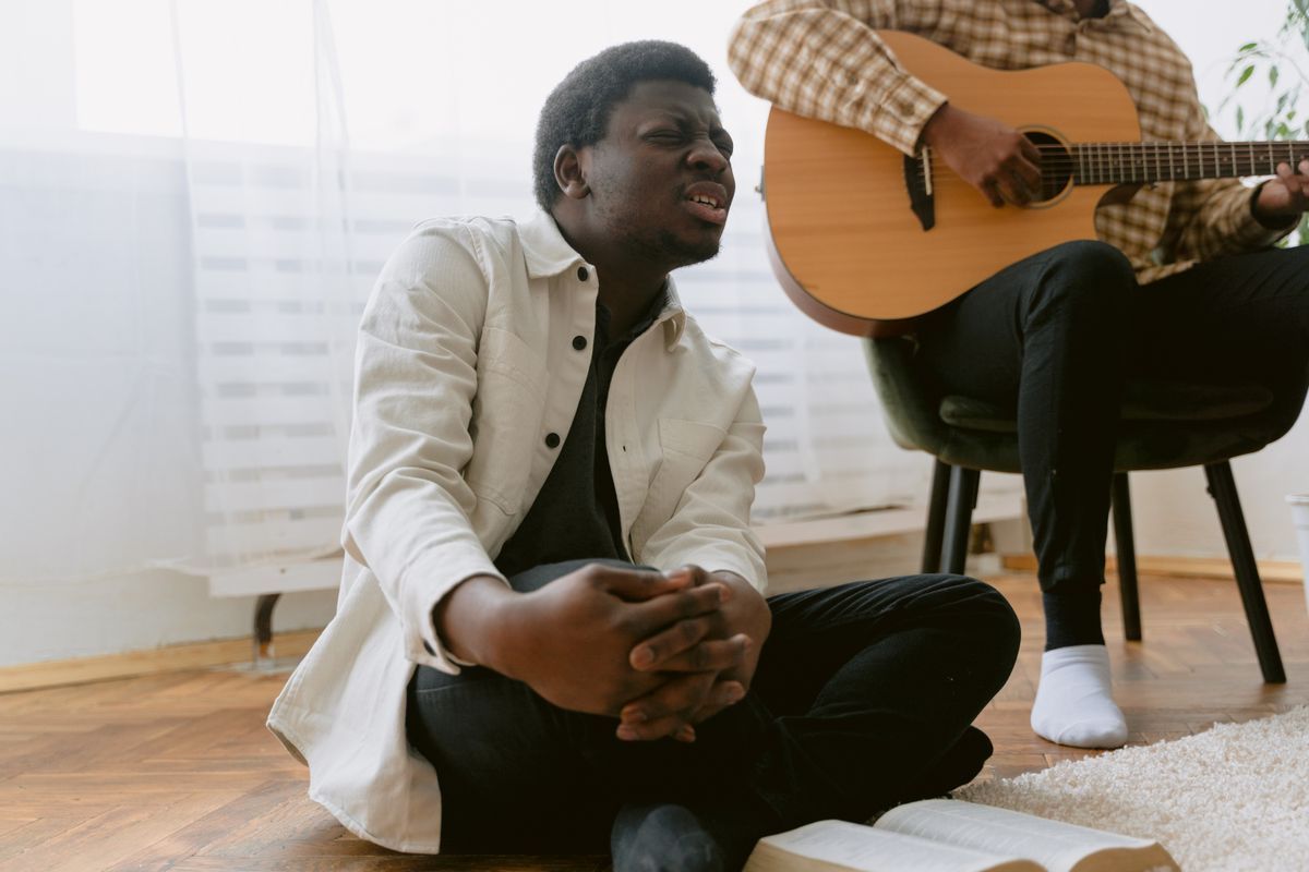A man singing in worship with an acoustic guitarist beside him