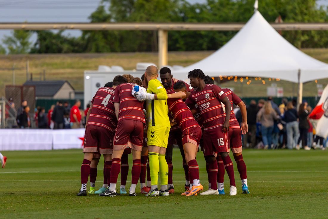 A diverse team in a pre-game huddle on the pitch