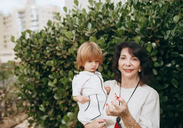 A grandmother holding her young grandchild outdoors