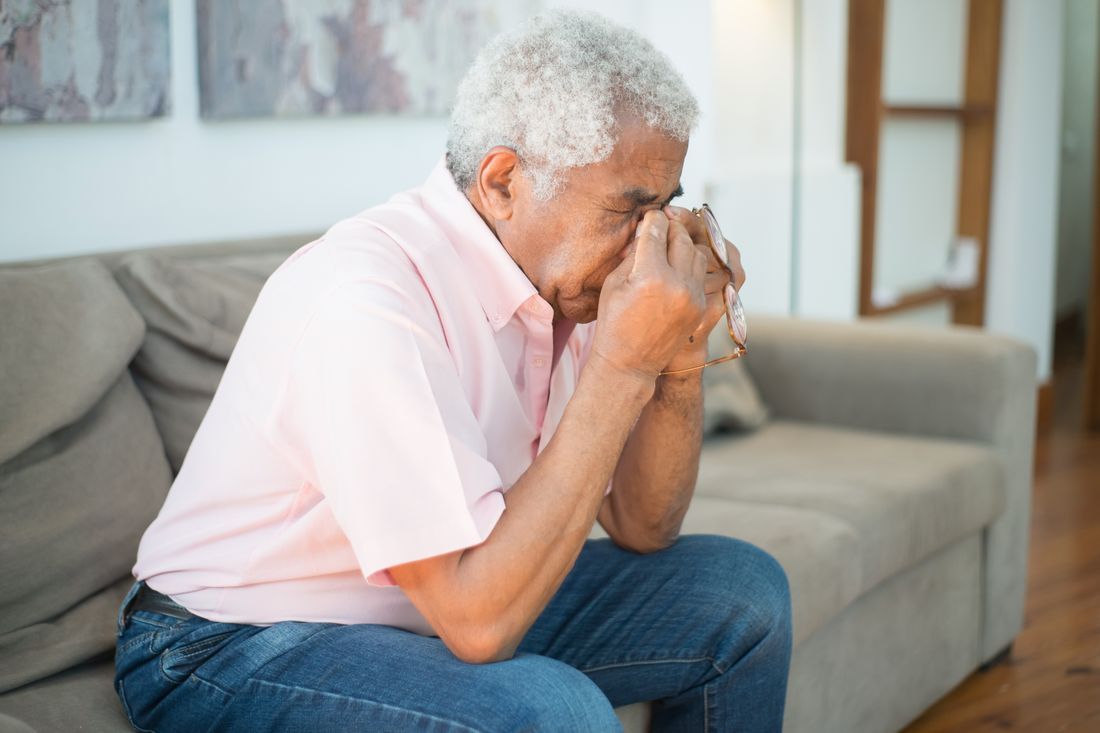 An older man resting his head in his hand in quiet grief