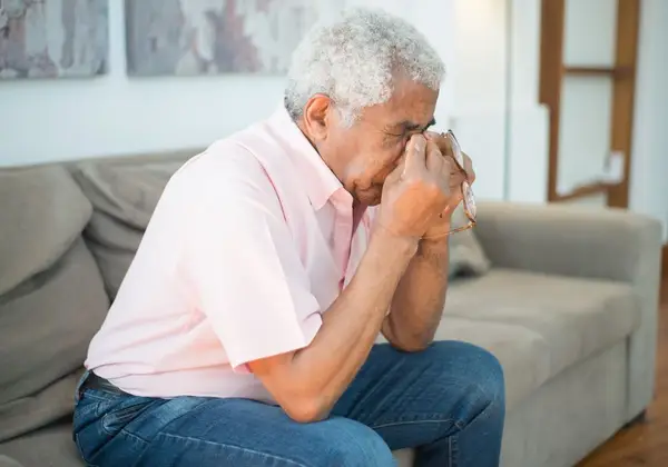 An older man resting his head in his hand in quiet grief