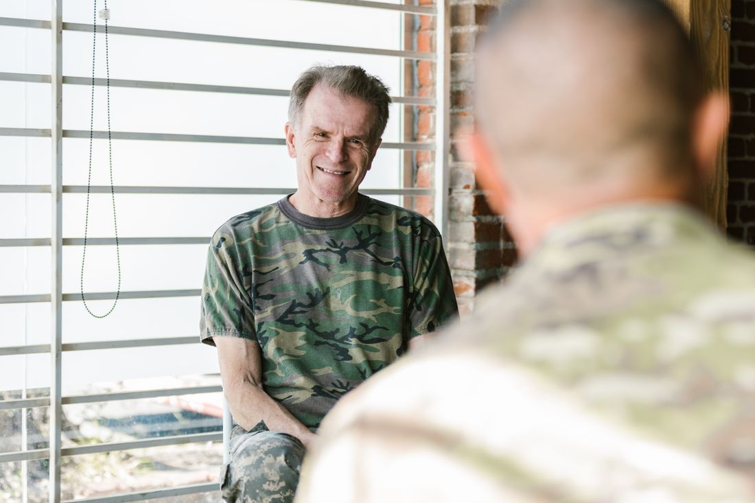 An older veteran smiling as he talks with a fellow veteran
