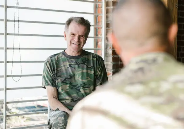 An older veteran smiling as he talks with a fellow veteran