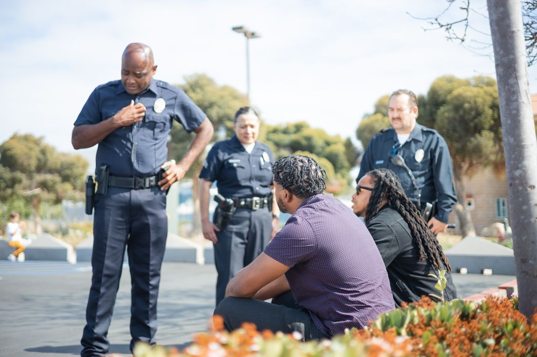 An officer talking with people seated outdoors