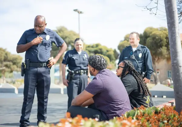 An officer talking with people seated outdoors