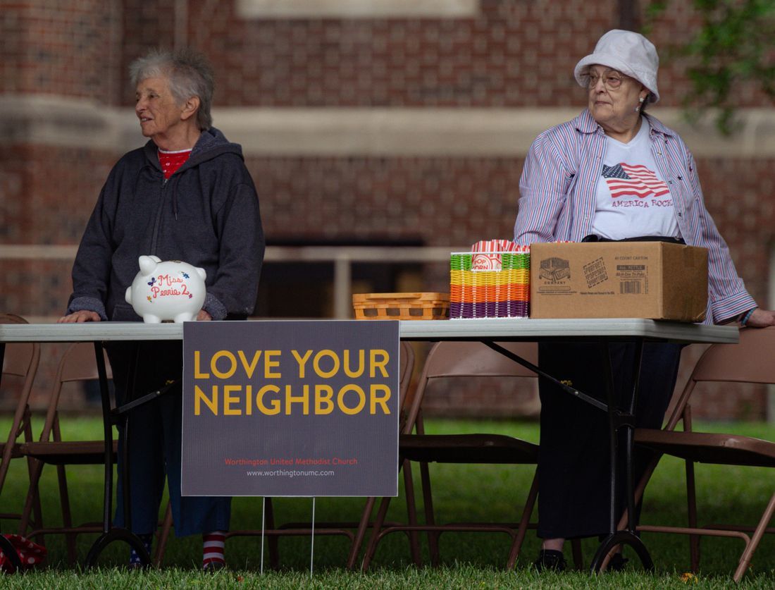 Two faithful volunteers serving at a church 'love your neighbor' table