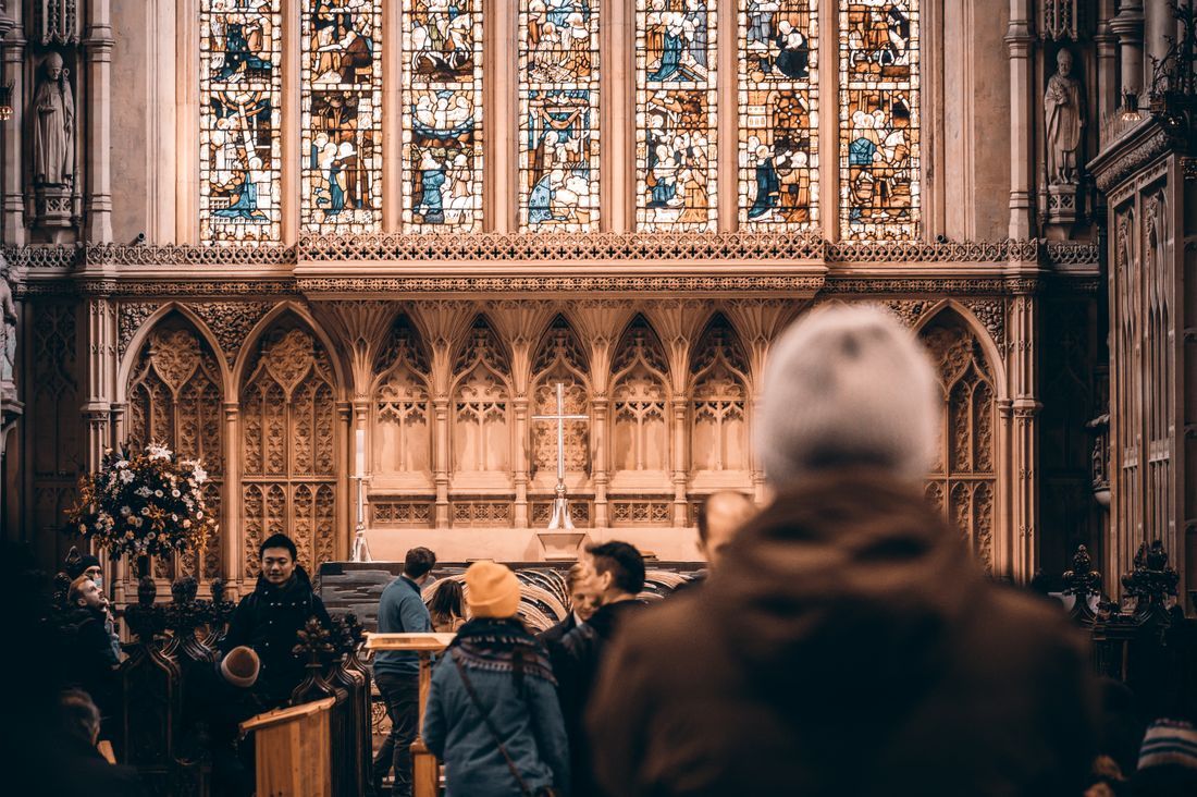 Worshippers gathered before a stained-glass cathedral altar