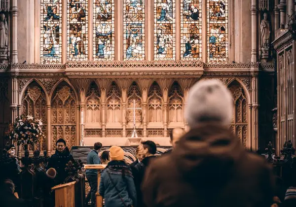 Worshippers gathered before a stained-glass cathedral altar