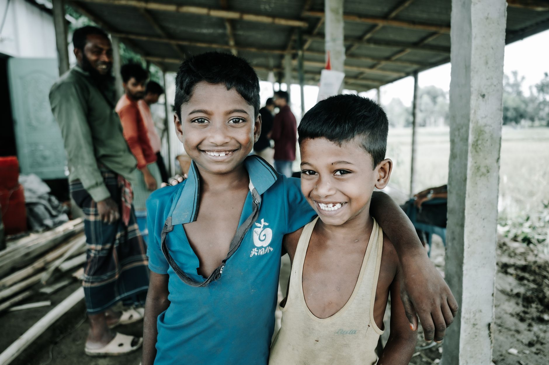 Two Bangladeshi boys smiling together in a village