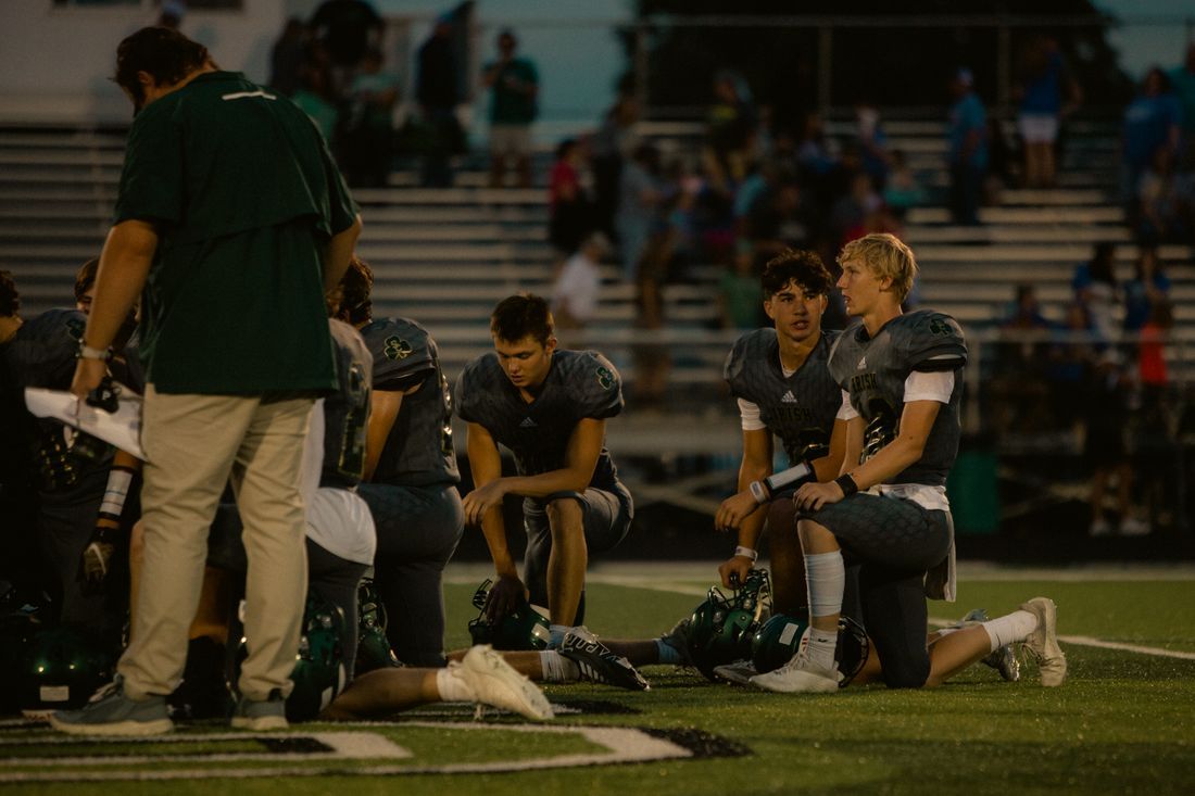 A football team kneeling together at dusk