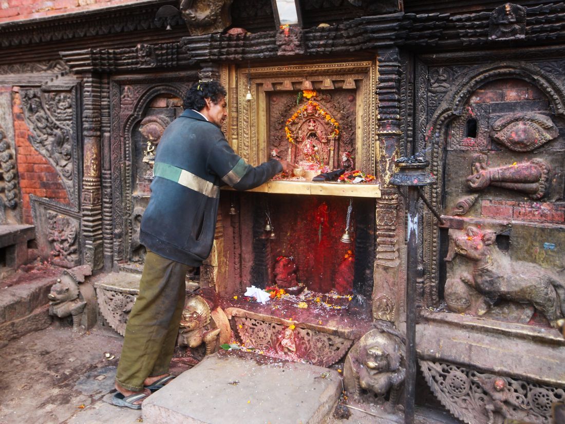 A man offering prayers at an ornate shrine