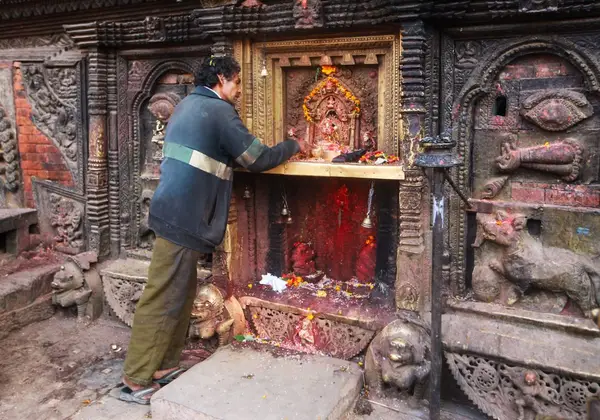 A man offering prayers at an ornate shrine