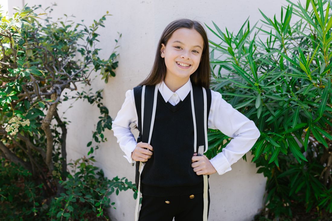 A confident middle school girl smiling with her backpack