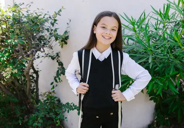 A confident middle school girl smiling with her backpack