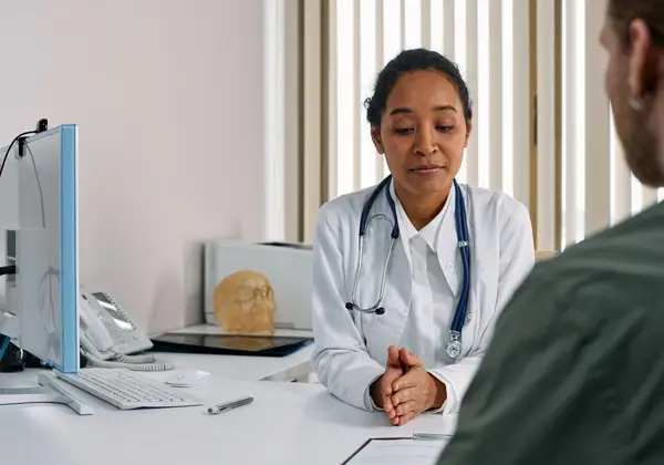 A doctor sitting with a patient, carrying the weight of hard news