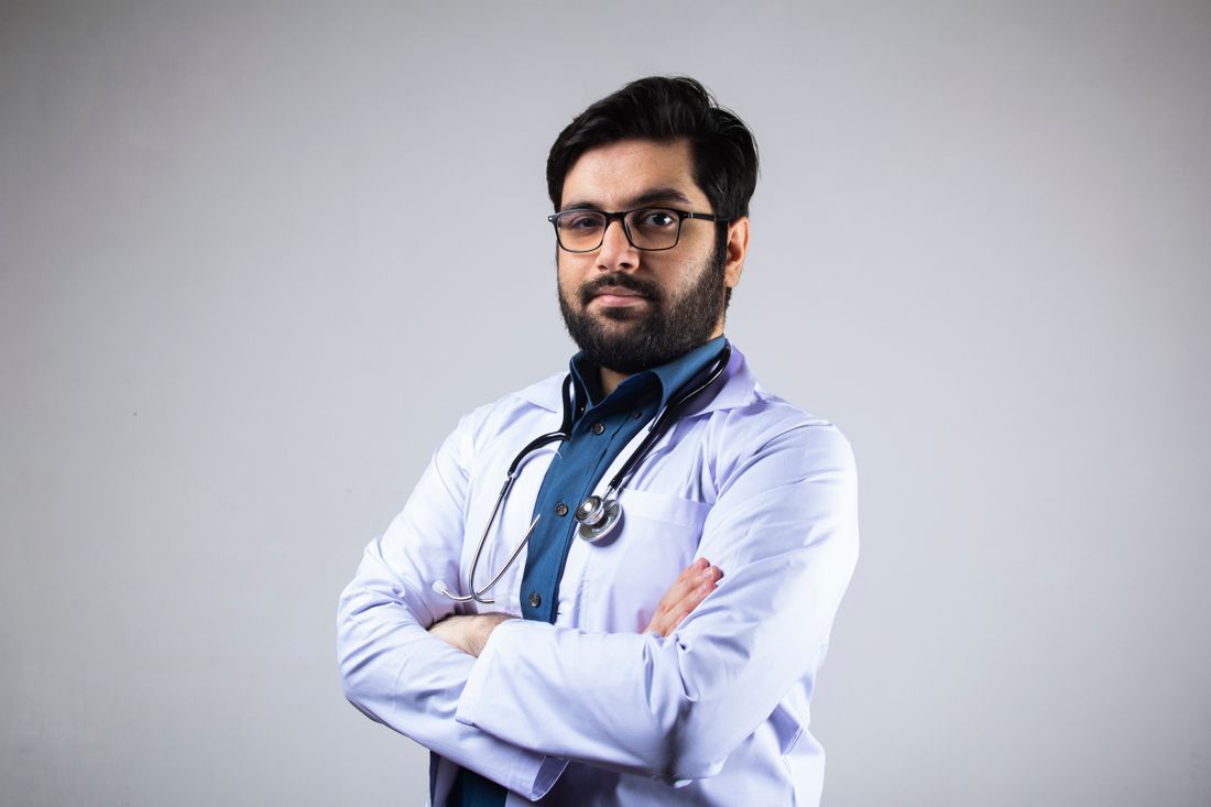 A physician standing with arms crossed in a clinical portrait