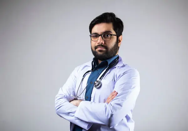 A physician standing with arms crossed in a clinical portrait