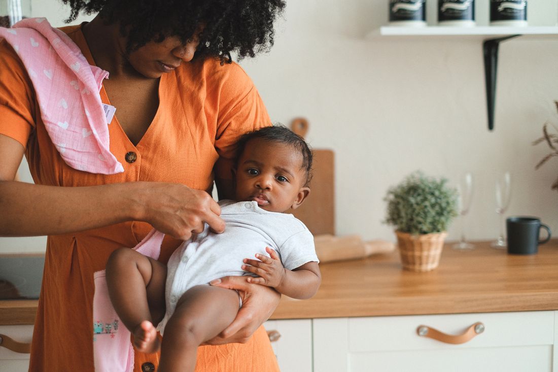 A mother holding her baby in the kitchen during an everyday moment
