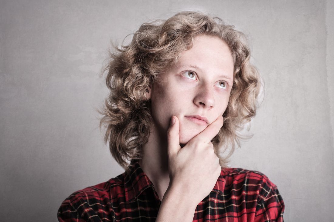 A young person lost in thought, hand to chin