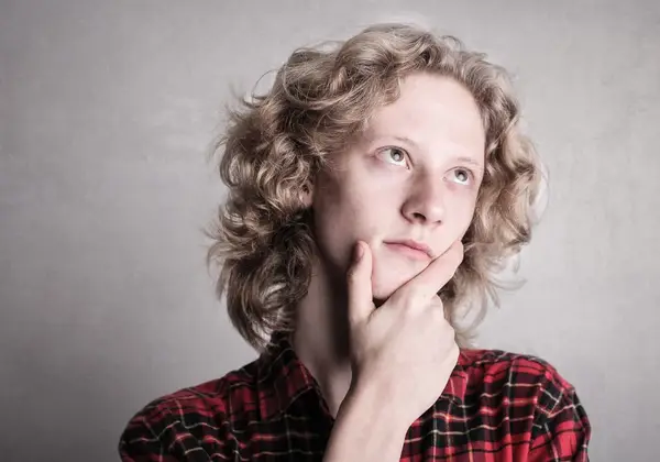 A young person lost in thought, hand to chin