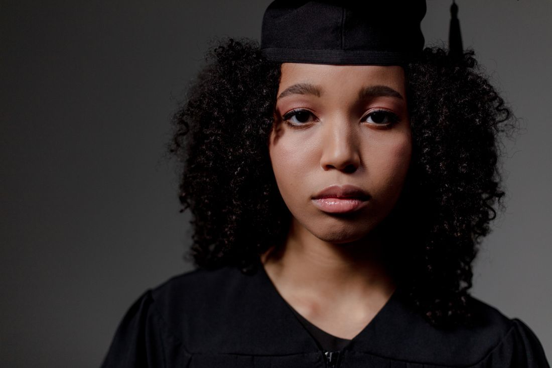 A graduate standing thoughtfully, looking to the future