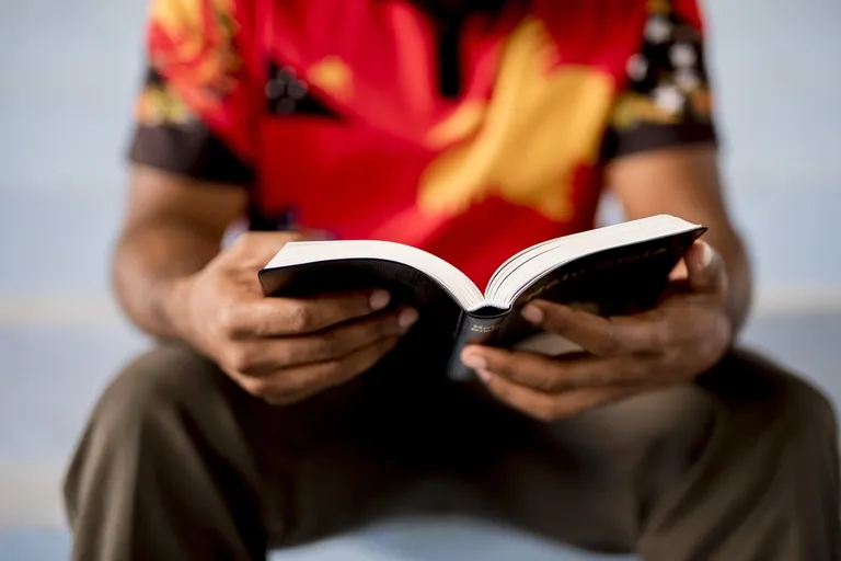 A man sits quietly absorbed in reading, soaking in the words on the page — a picture of receiving the Father's love each morning rather than performing for it.