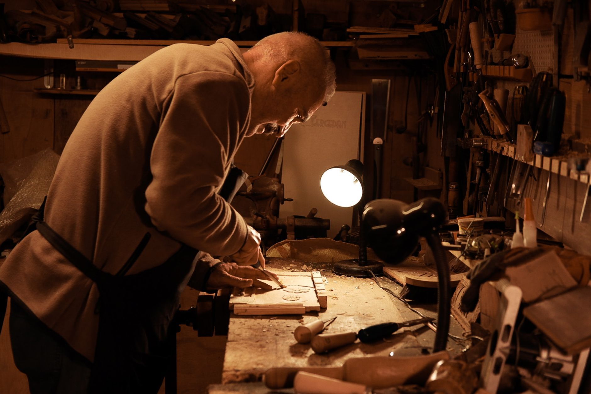 An older craftsman working by lamplight in his workshop