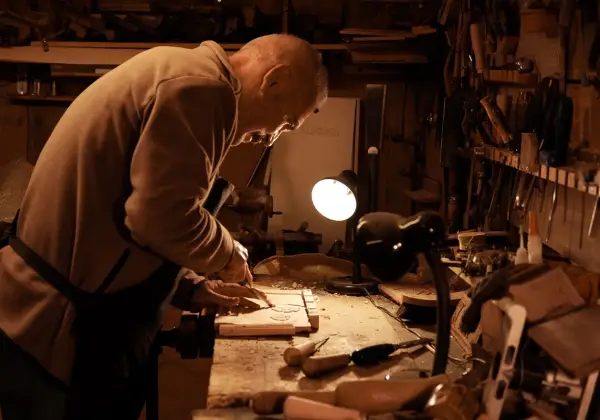 An older craftsman working by lamplight in his workshop