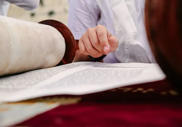 Reading from a Torah scroll with a silver pointer