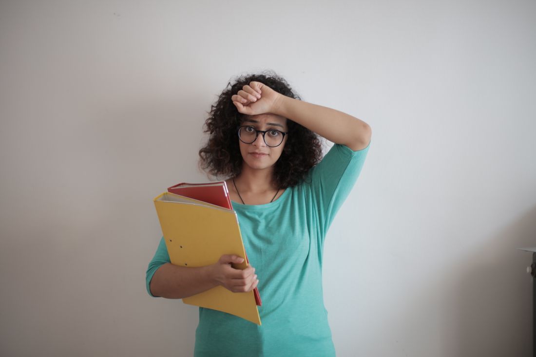 A woman pausing wearily with a hand to her brow