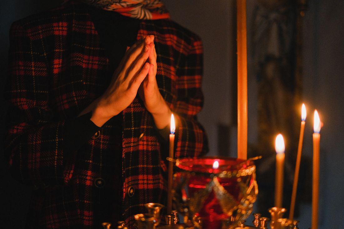 A worshipper praying beside lit devotional candles