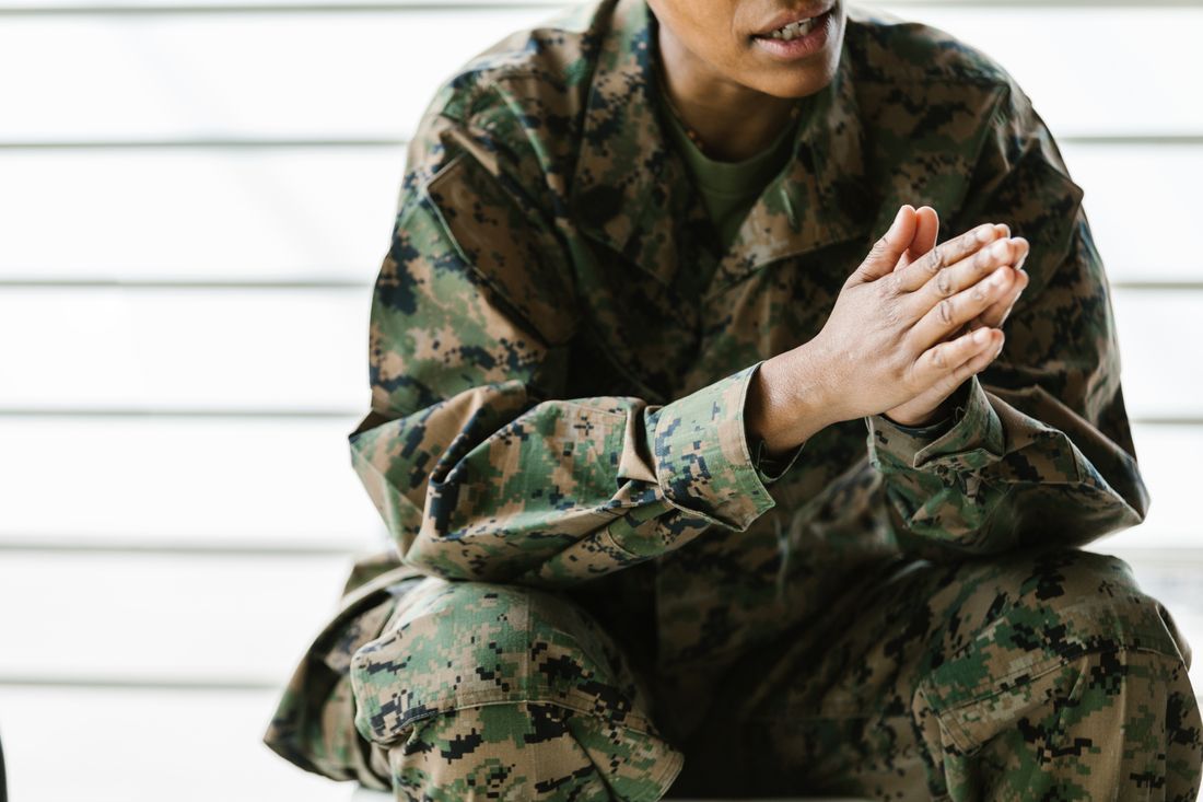 A Marine sitting with hands clasped, carrying the weight of service