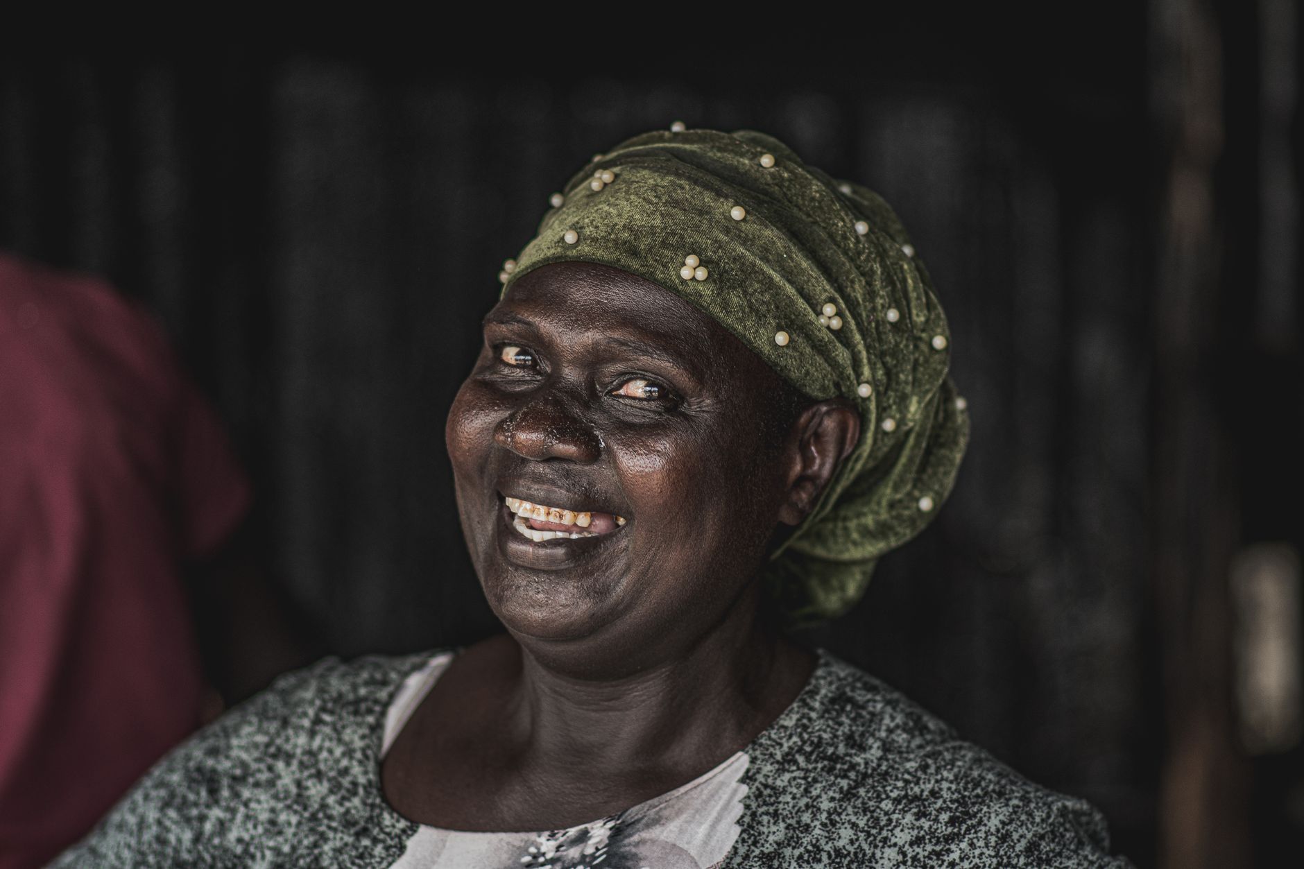 A joyful Ugandan woman with a green headscarf