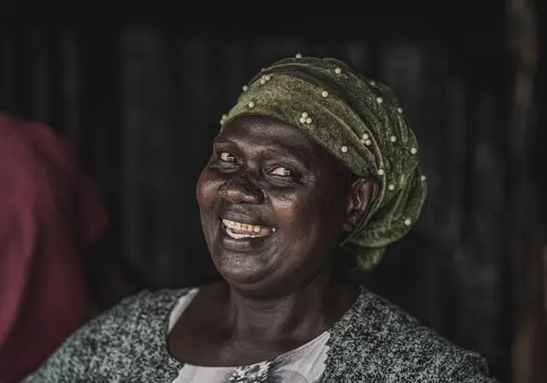 A joyful Ugandan woman with a green headscarf