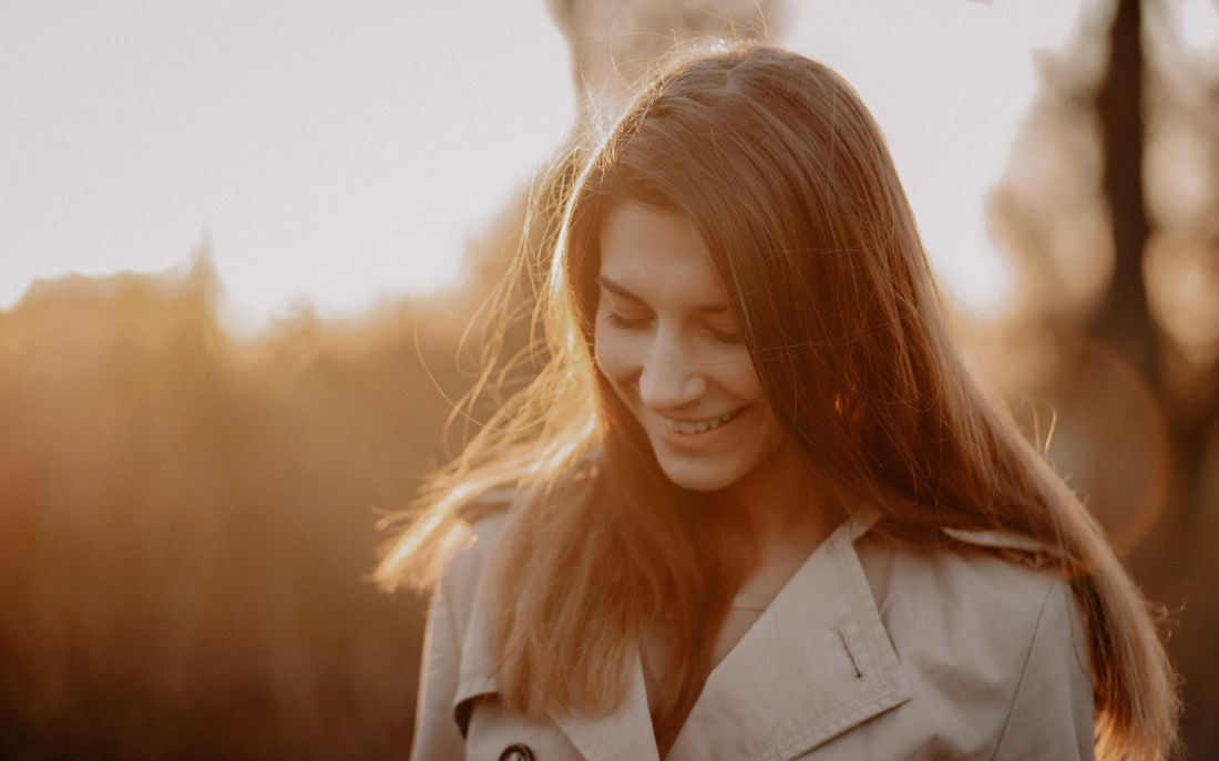 A woman smiling gently in golden evening light