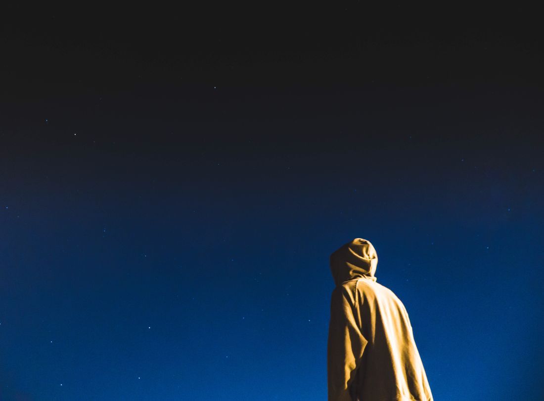 A person looking up into a deep blue starry sky