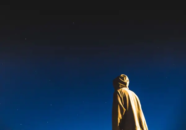 A person looking up into a deep blue starry sky