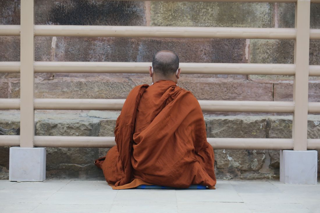 A monk seated in meditation before a temple wall