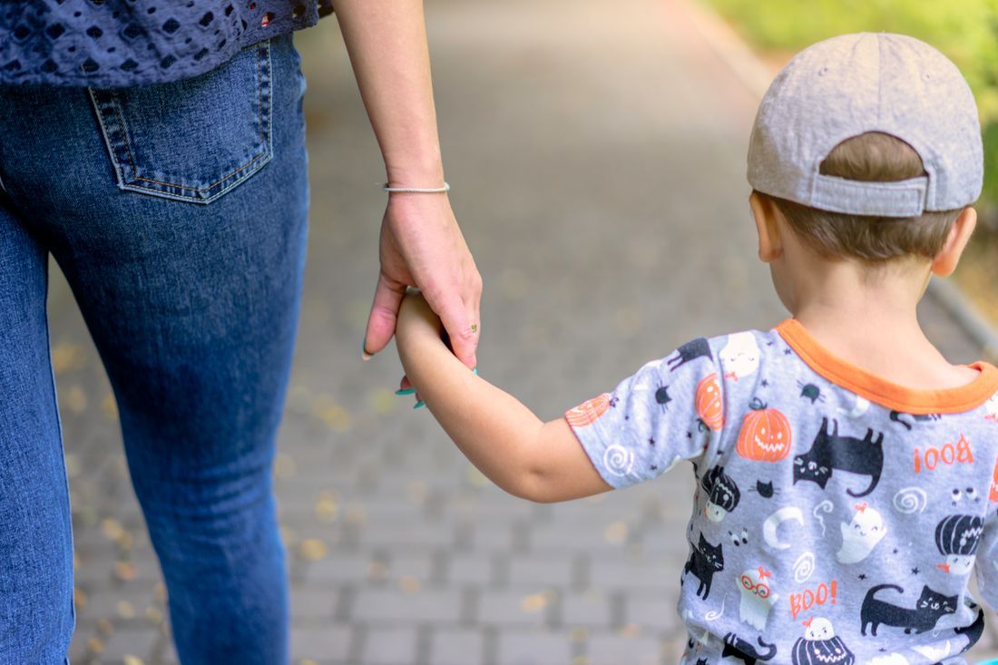 A mother holding her young son's hand as they walk