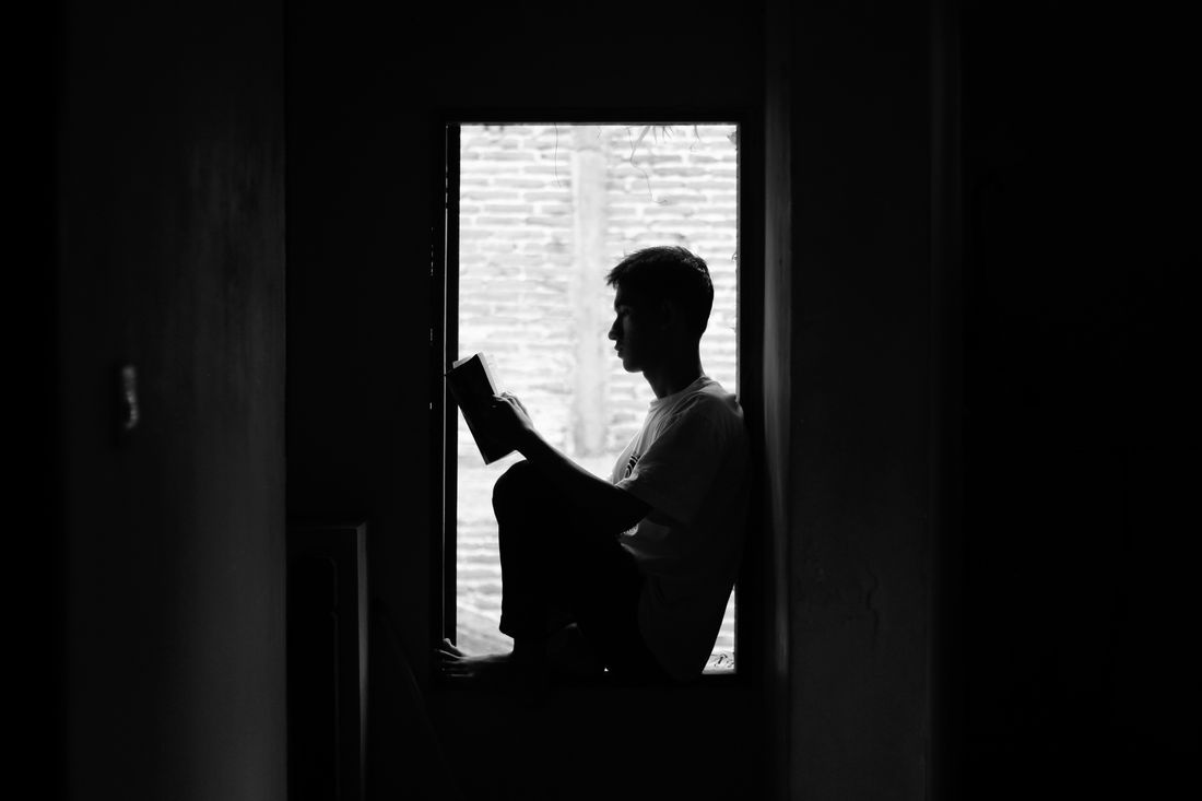 A young man reading by a window in the quiet