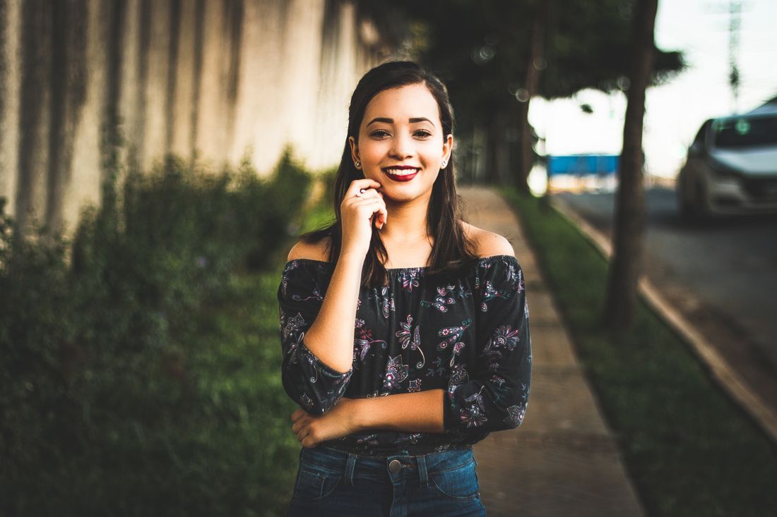 A young woman smiling on a tree-lined street at golden hour