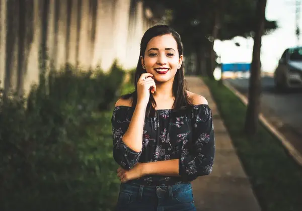 A young woman smiling on a tree-lined street at golden hour