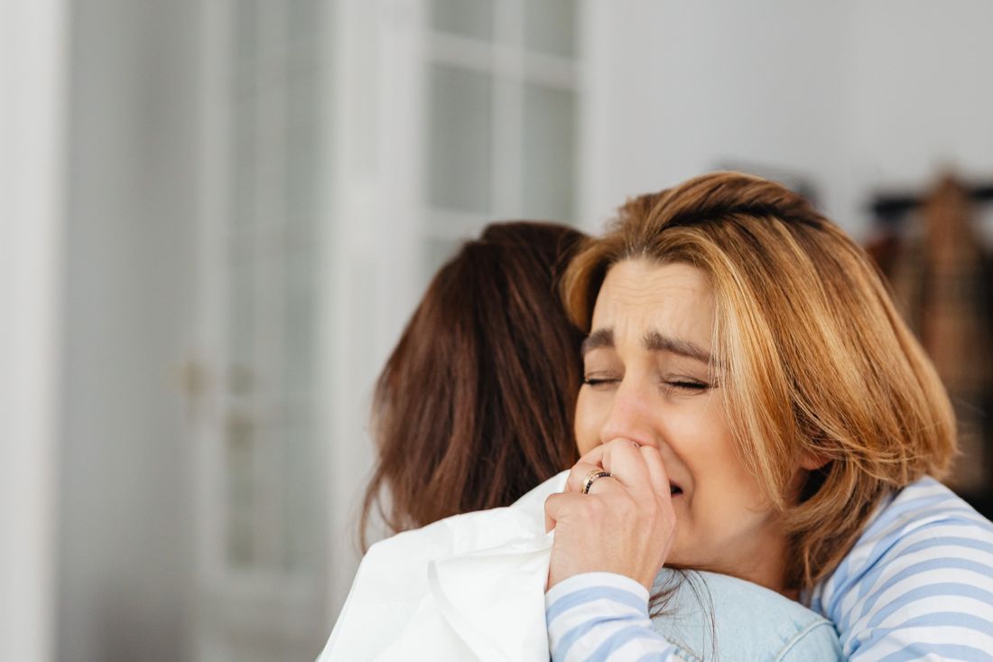 One woman holding another as she weeps, offering comfort