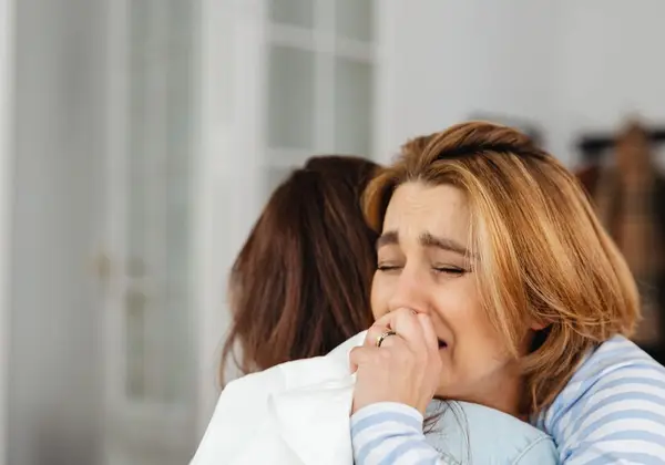 One woman holding another as she weeps, offering comfort
