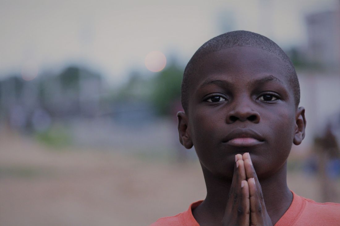 A young boy with his hands folded in prayer