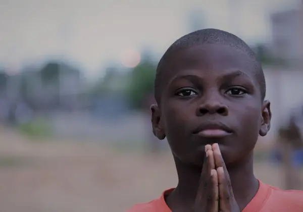 A young boy with his hands folded in prayer